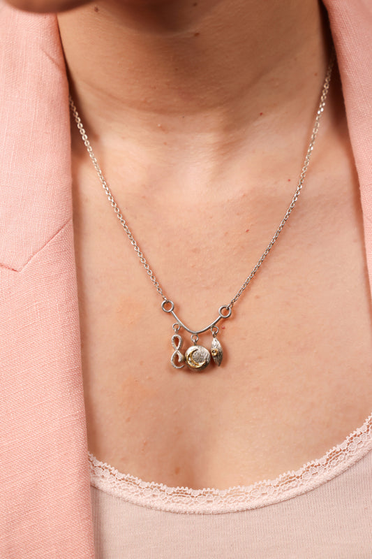 Close-up of the infinity, evil eye, and crescent charm detailing on the Ari Necklace