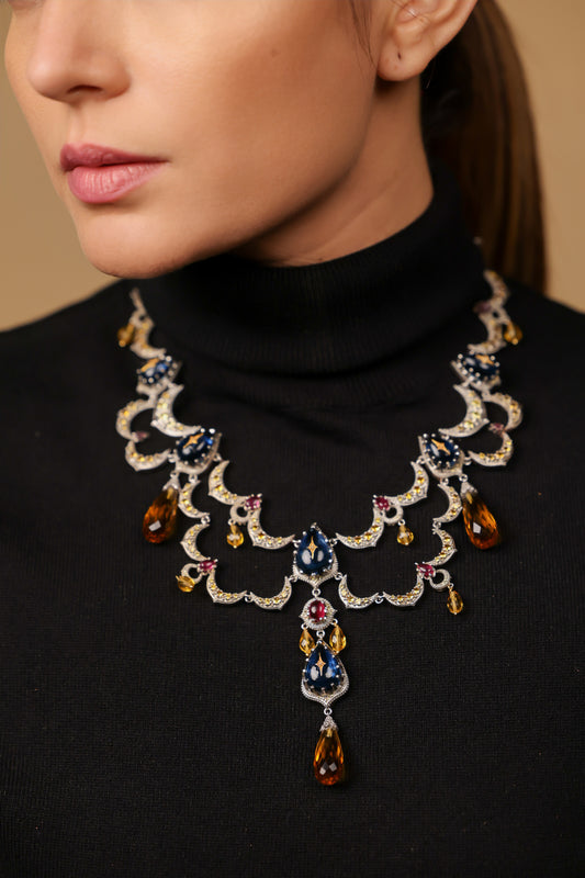 Close-up of the Sara Necklace showing the diamond milgrain edging and ruby accents along the crescent moon arches